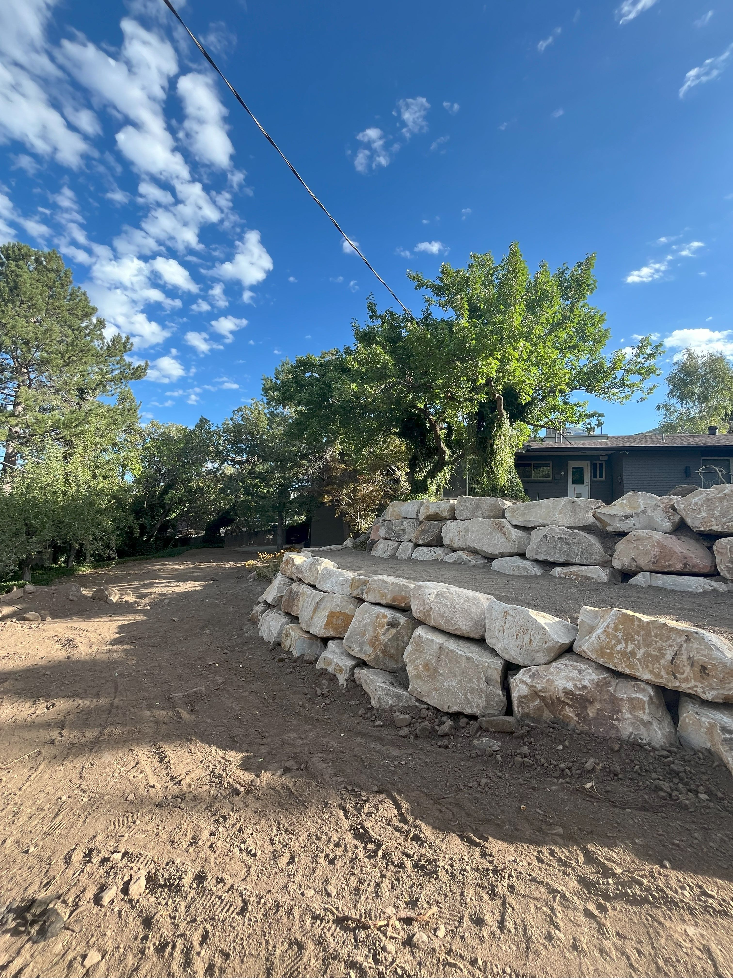 Boulder retaining wall construction underway in Holladay backyard project.