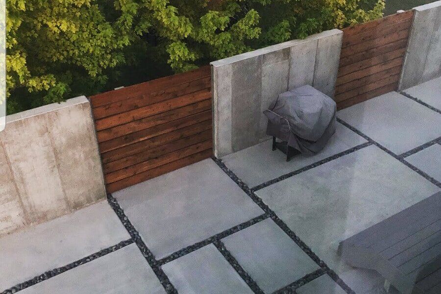 Modern concrete patio with dark gravel joints and horizontal wood privacy fencing