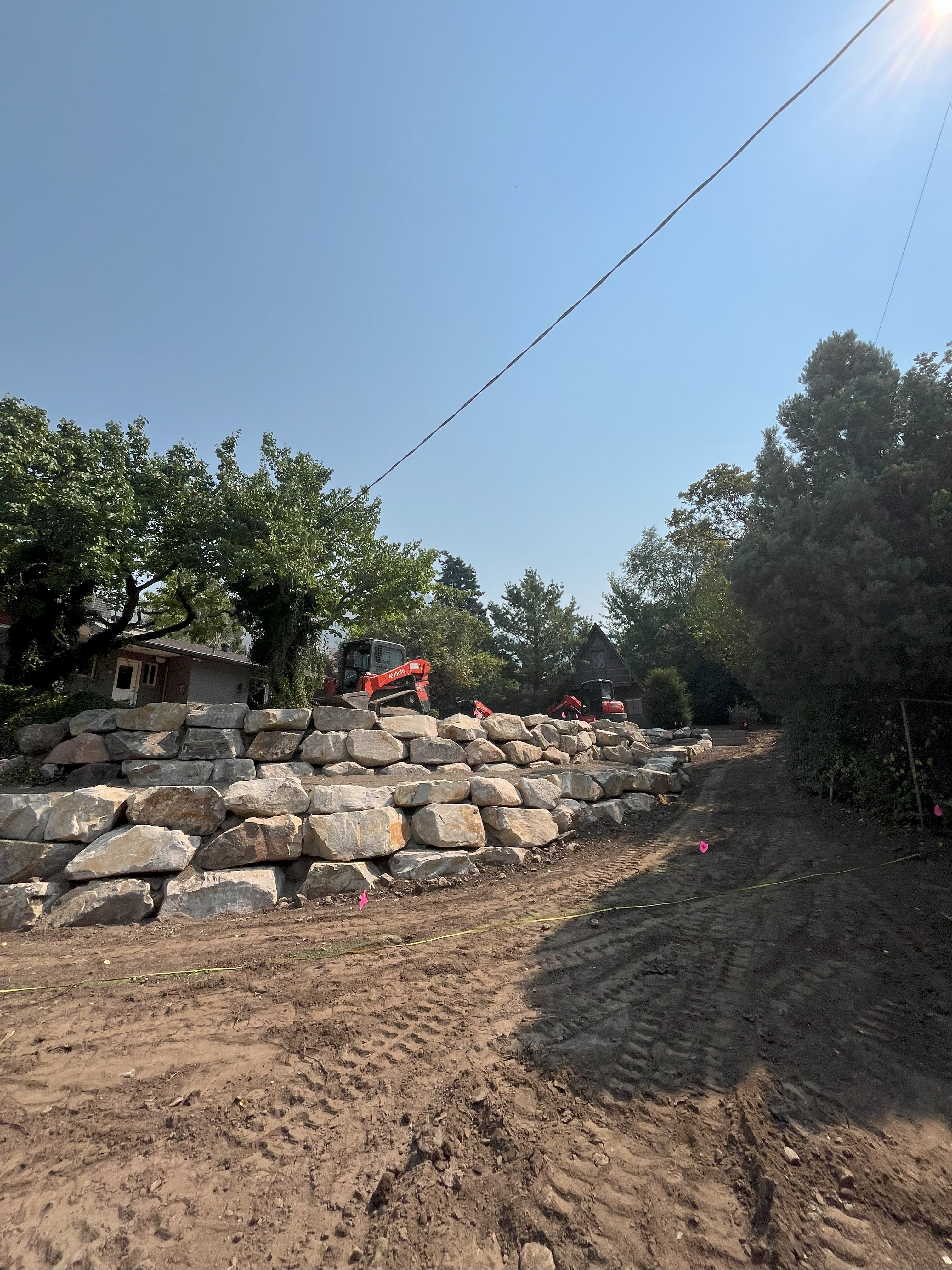 Large boulders being set for retaining wall installation in Holladay, Utah.