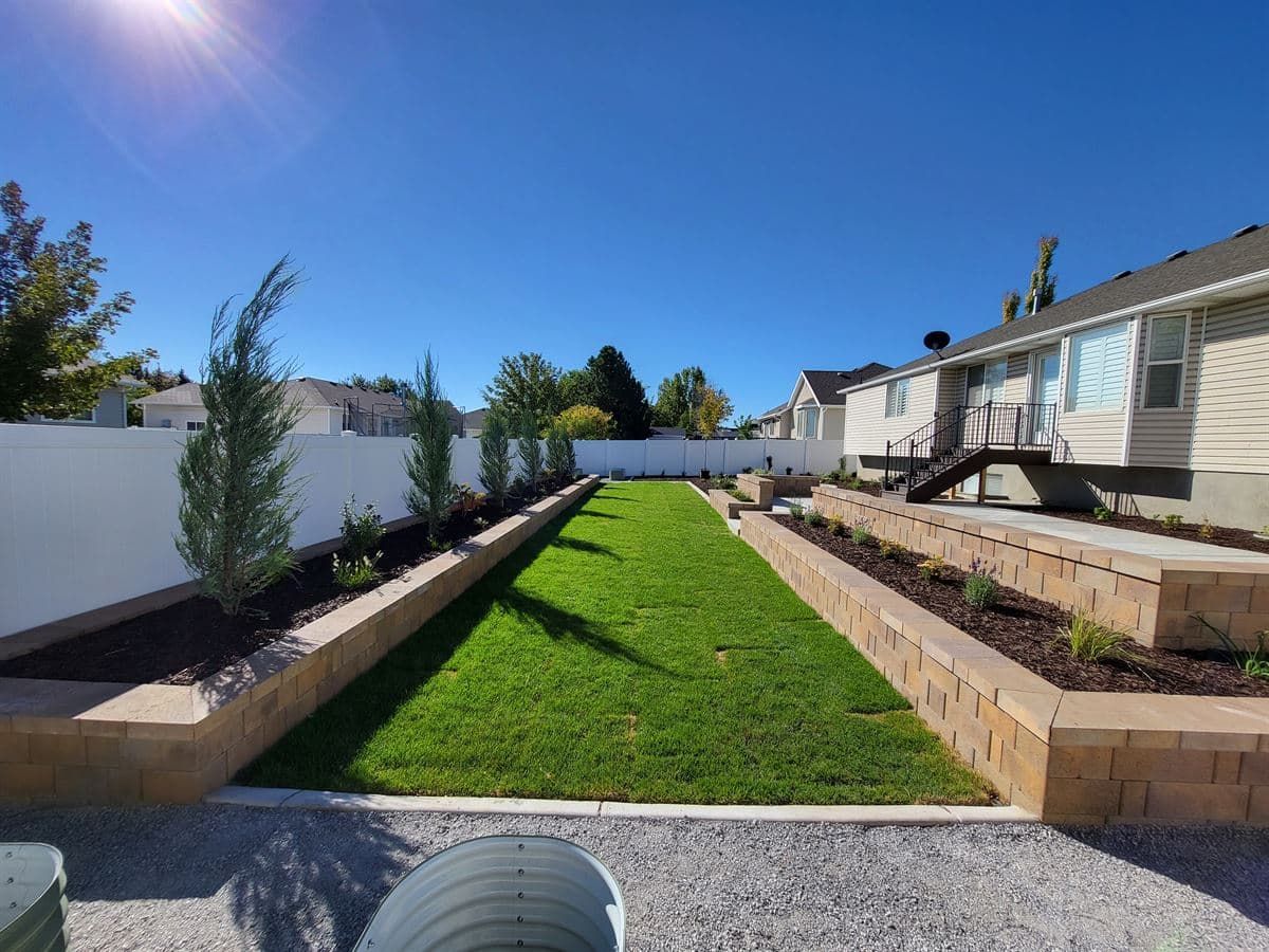 Tiered block retaining walls framing a finished lawn and new planting beds