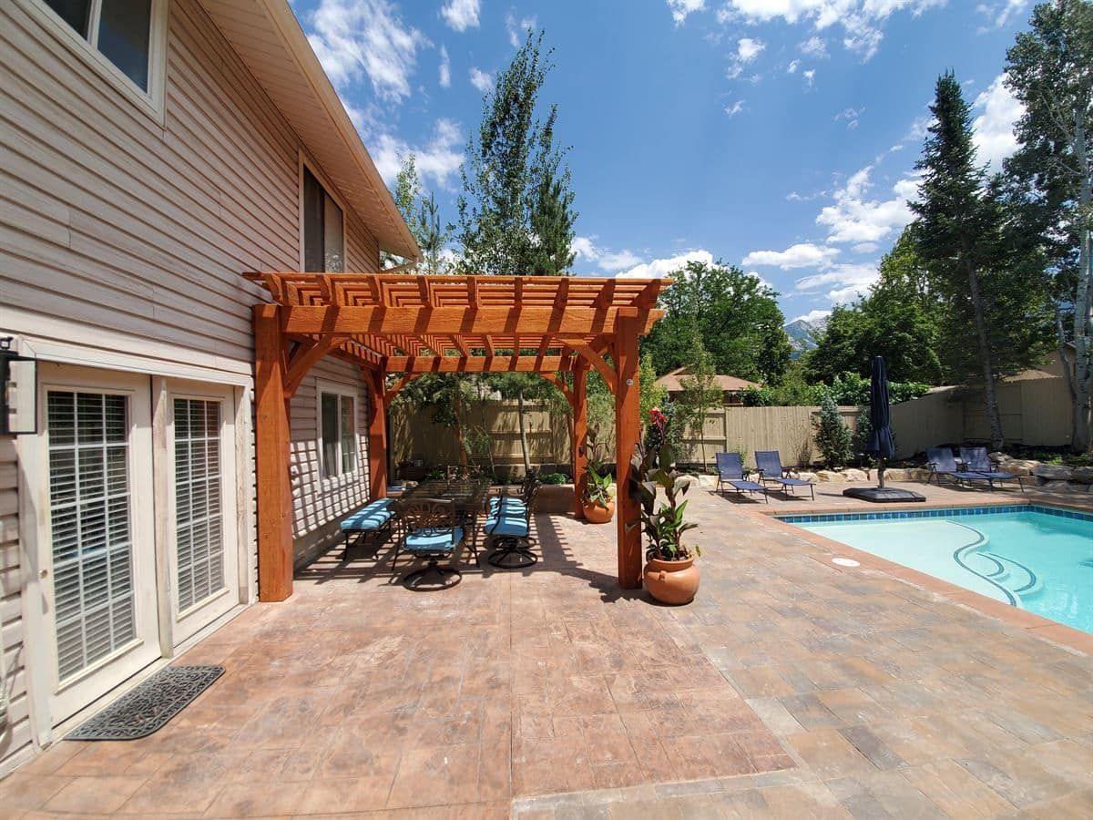 Side view of paver patio and pergola in Sandy backyard pool and outdoor living project.