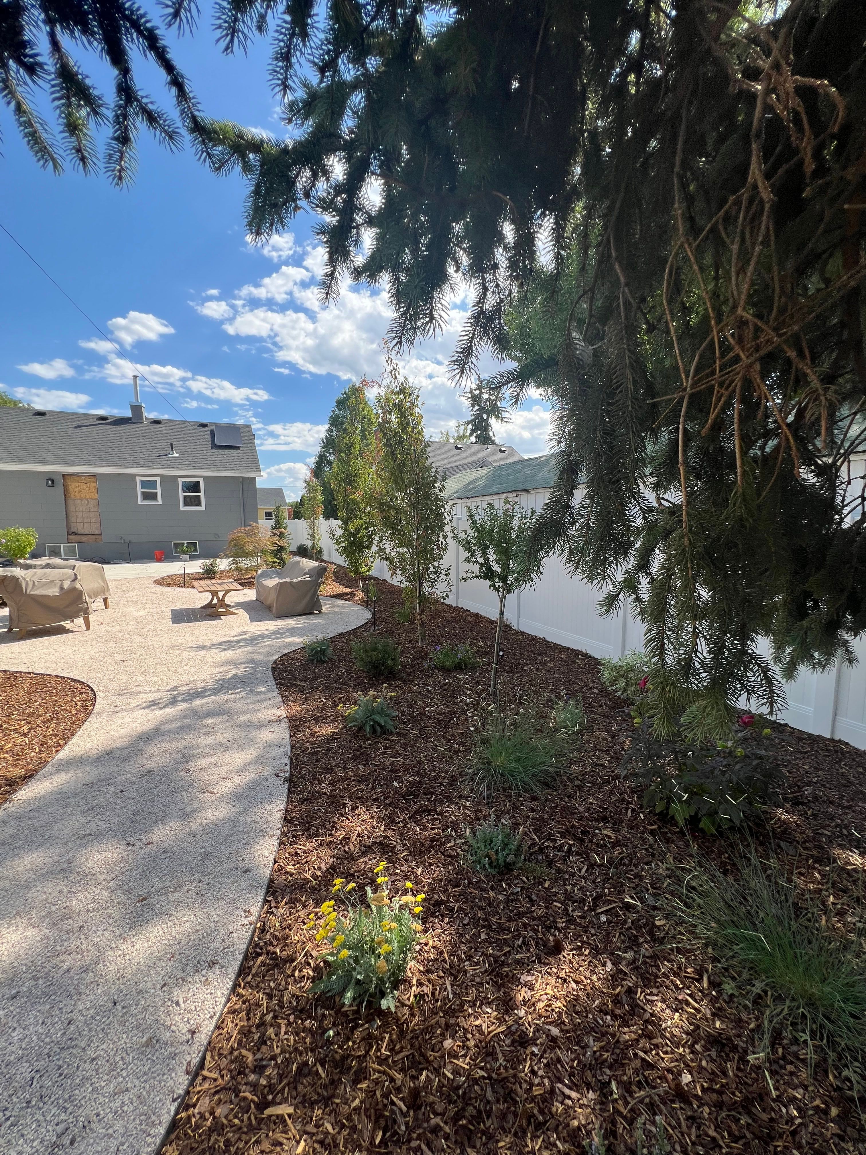 Millcreek xeriscape walkway with layered drought-tolerant plants and natural bark mulch.