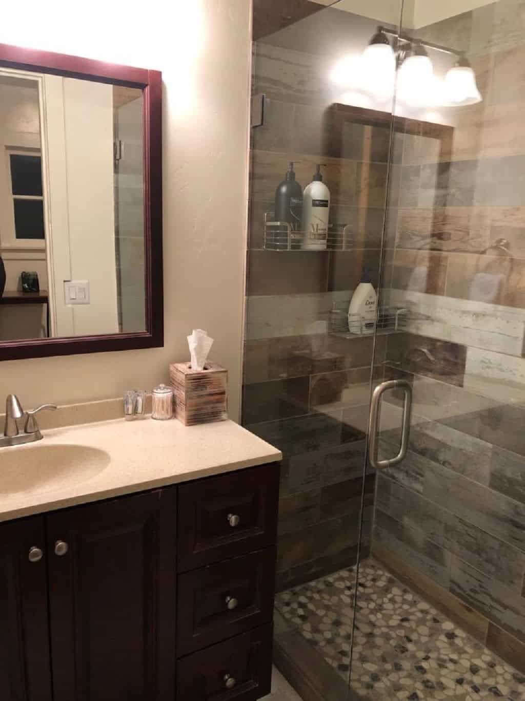 Completed bathroom remodel with a glass-enclosed tile shower and dark wood vanity.