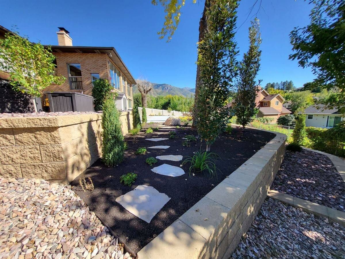 Tiered retaining walls with stone steps, new plantings, and mountain views