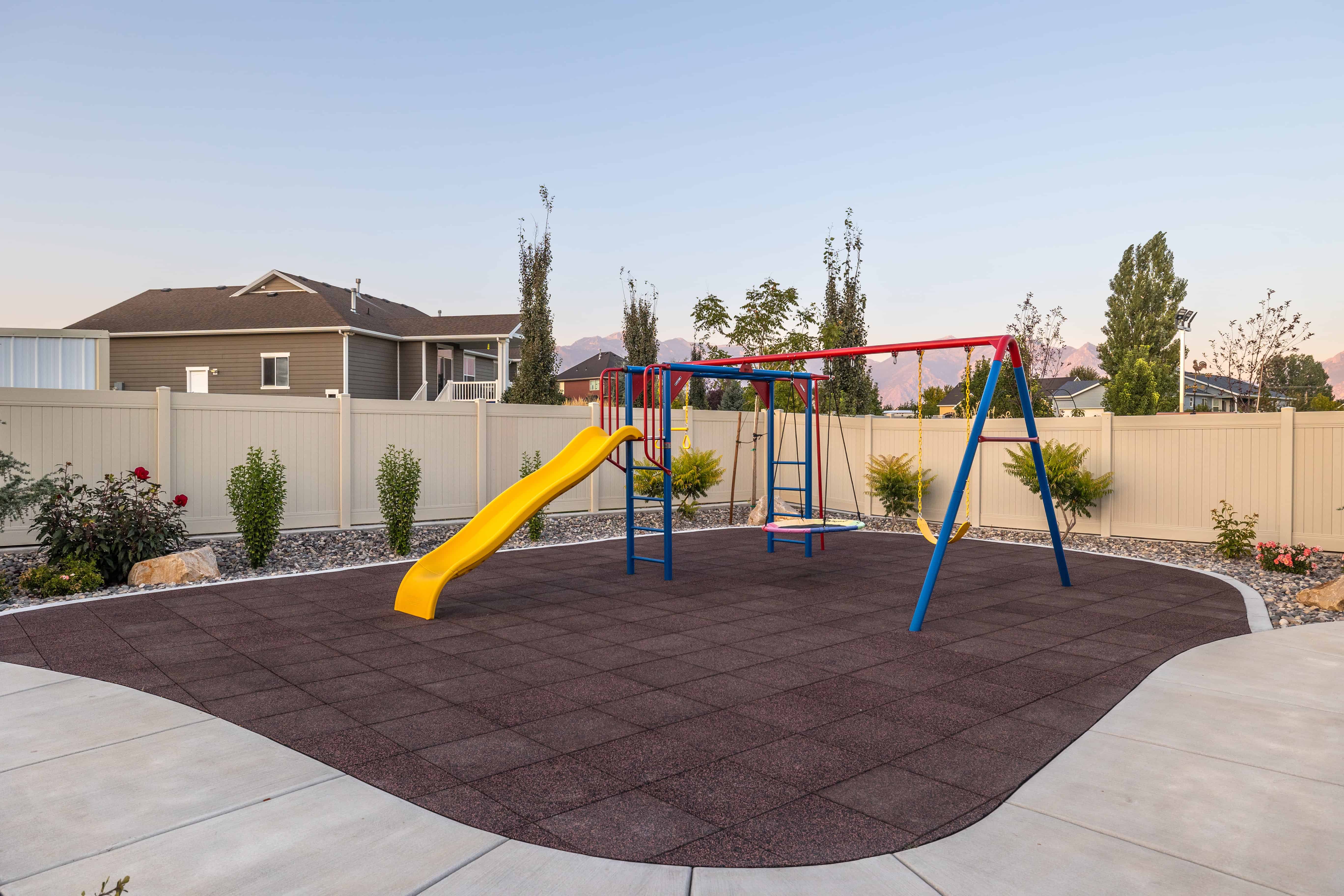 A backyard playground in Lehi with gravel surrounding, part of a xeriscaping project.