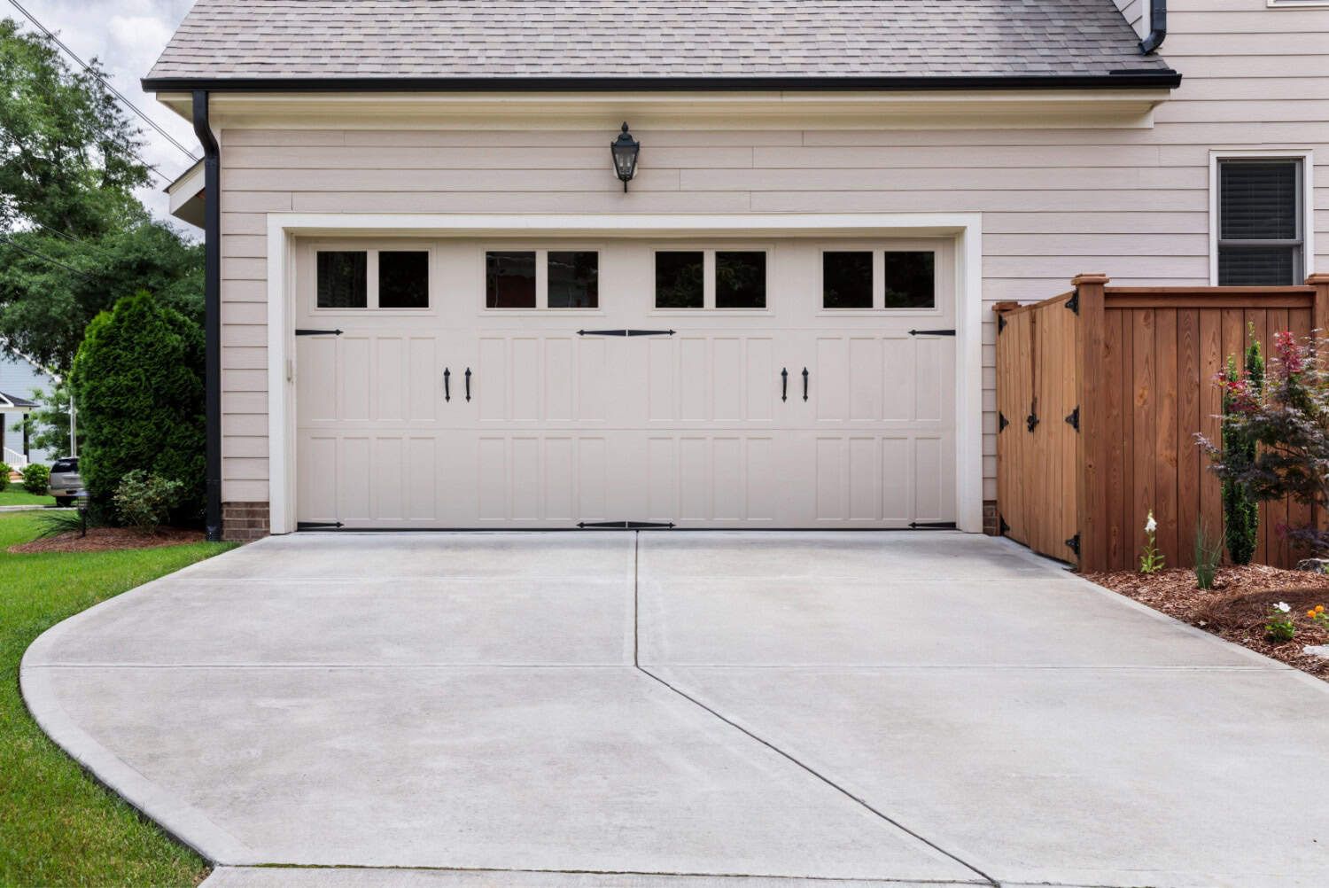 Finished detached garage with a new concrete driveway and wood privacy gate