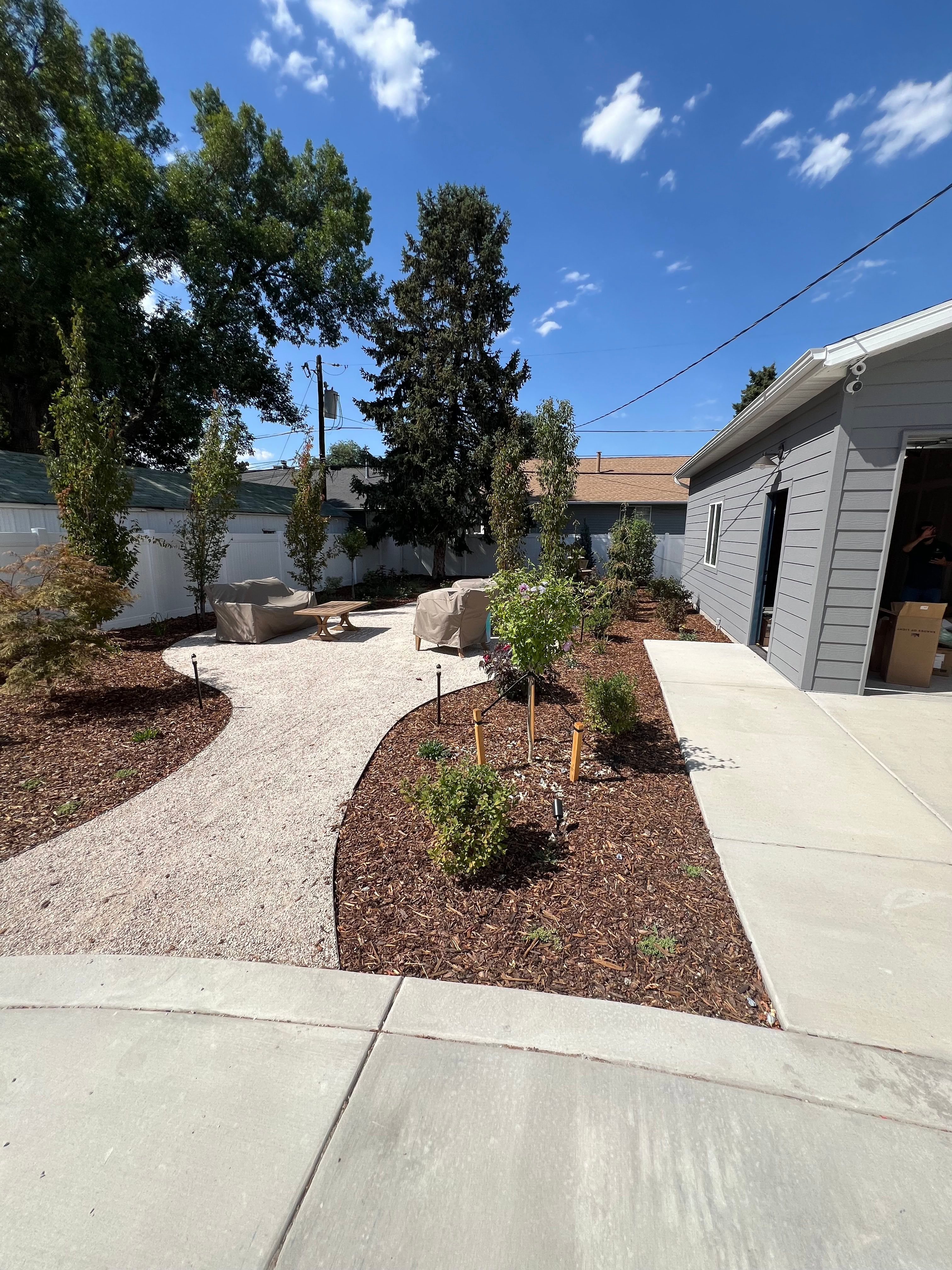 New xeriscape garden with a curving gravel path beside a detached garage.