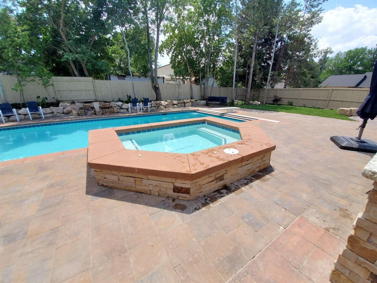 Backyard pool and hot tub in Sandy with custom paver deck and surrounding landscape.