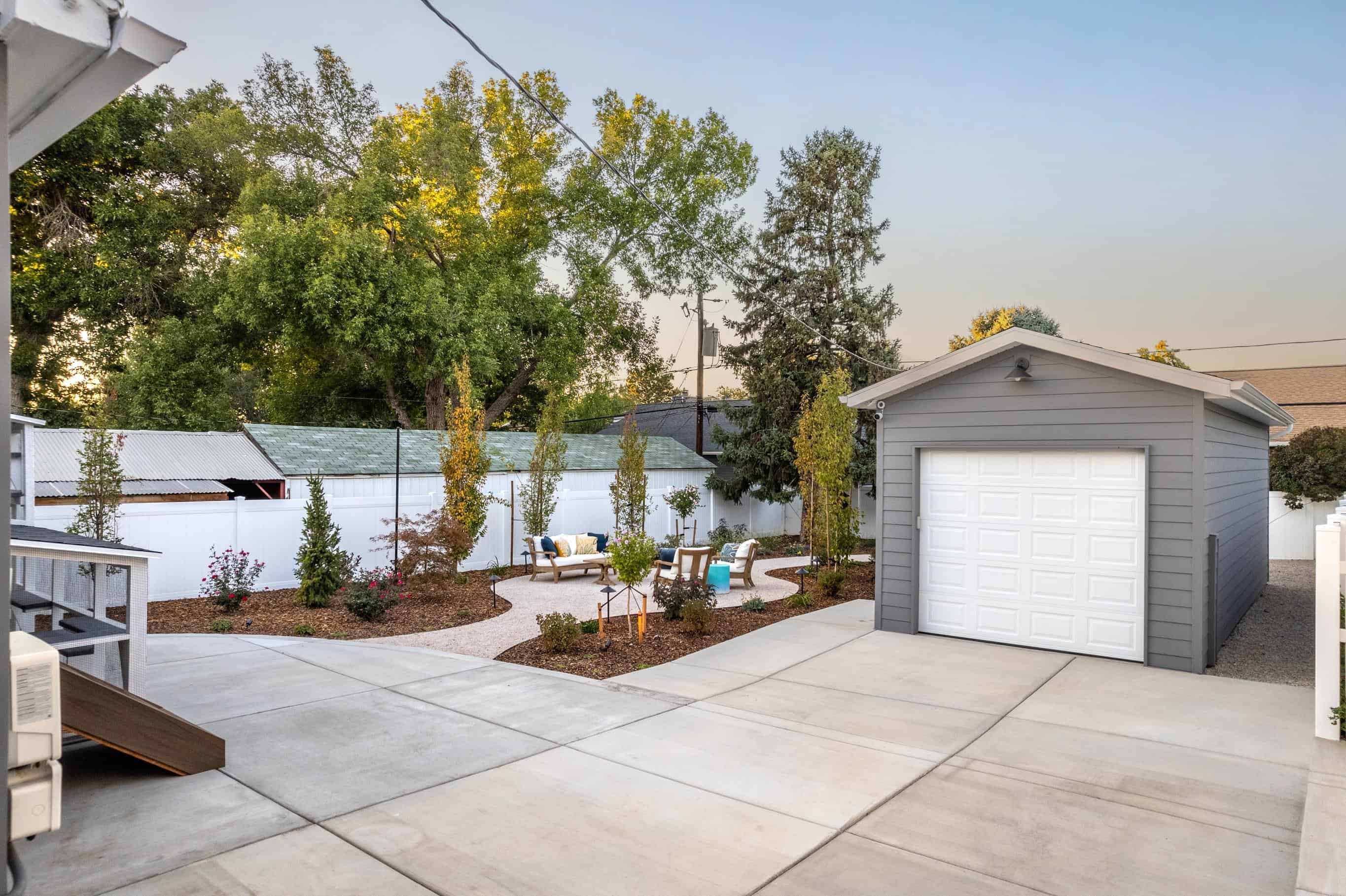 Completed detached garage beside a concrete driveway and water-wise backyard landscape
