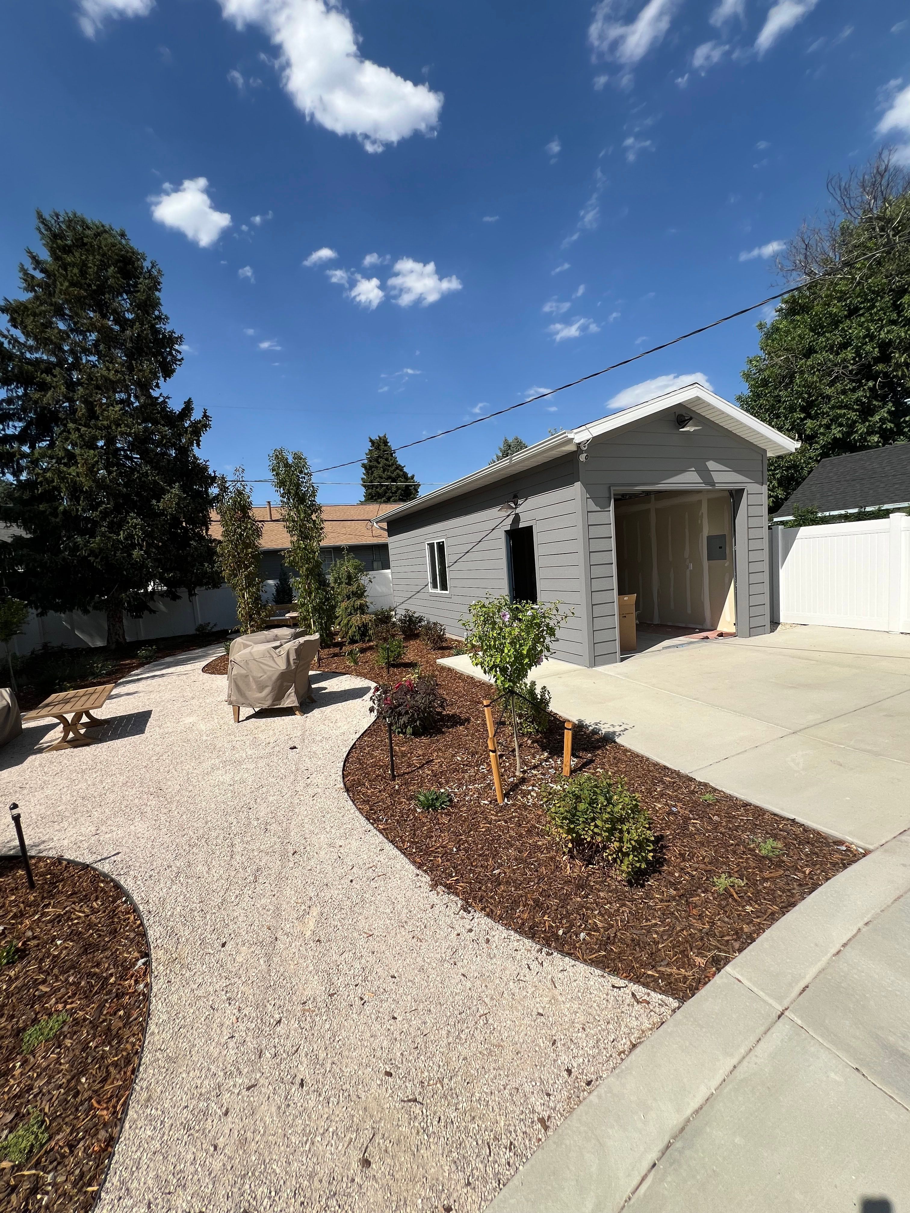 Curving gravel path and water-wise planting beds beside a detached garage under construction.