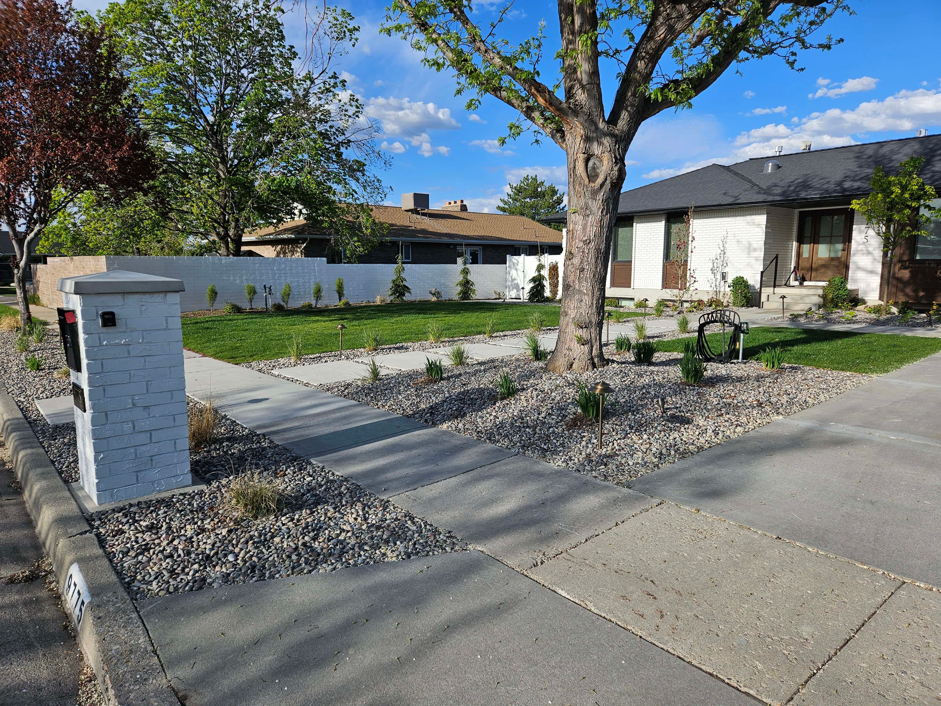 Front yard xeriscaping in South Jordan with drought-tolerant plants, decorative rock, and sod for curb appeal and water efficiency.
