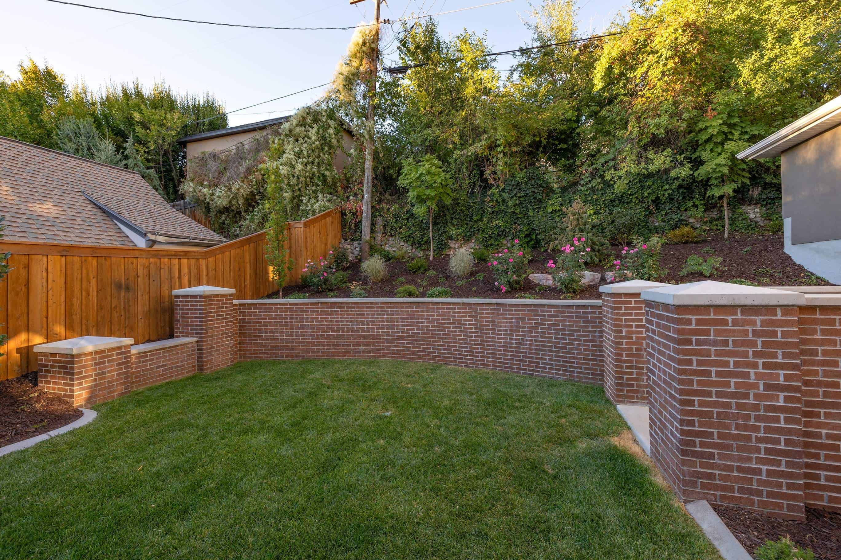 Upper section of the retaining wall made of brick, with a grass lower section in Federal Heights, Utah.
