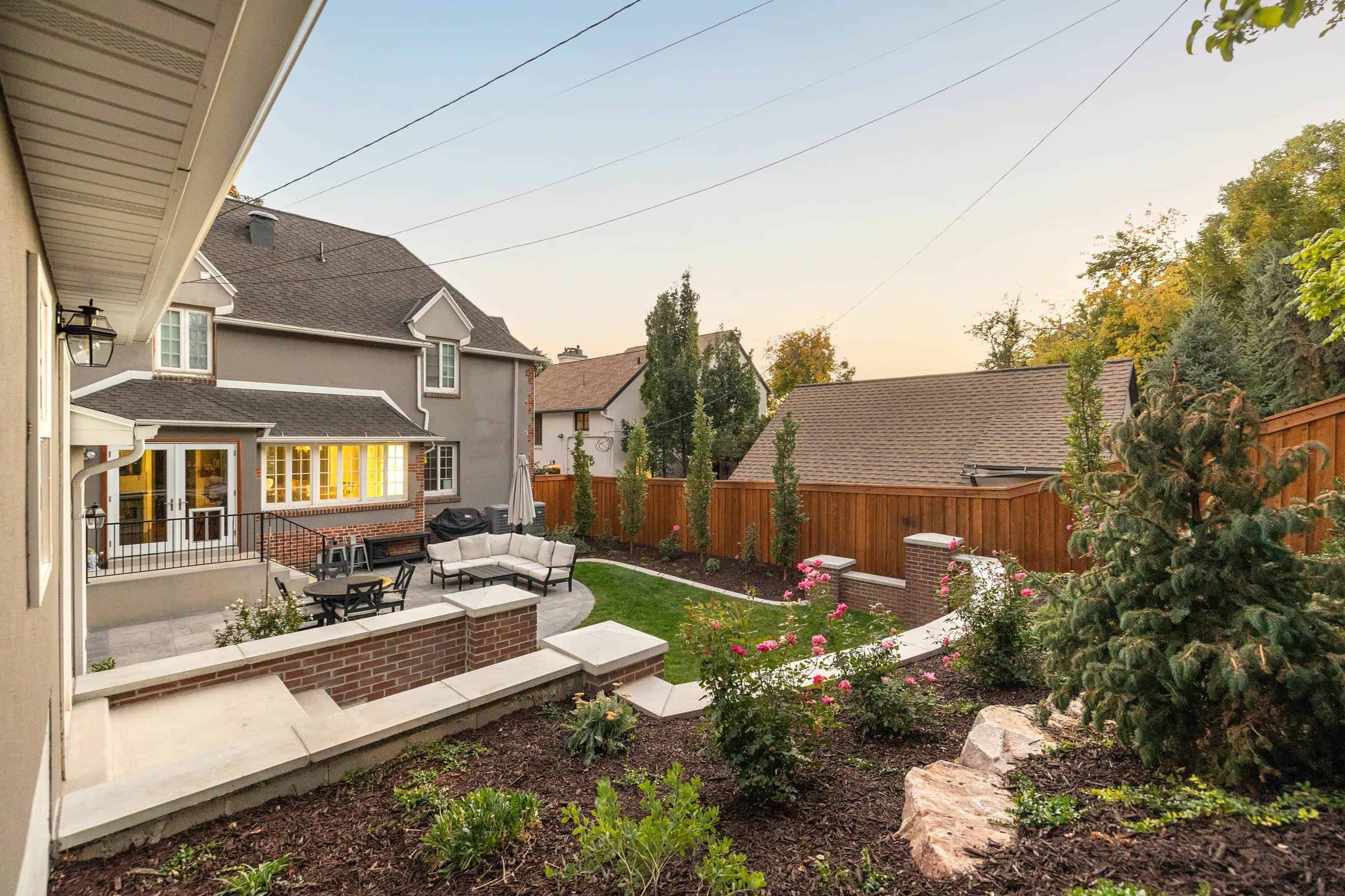 Completed landscape design in Salt Lake City with a retaining wall, paver walkway, and lush greenery.