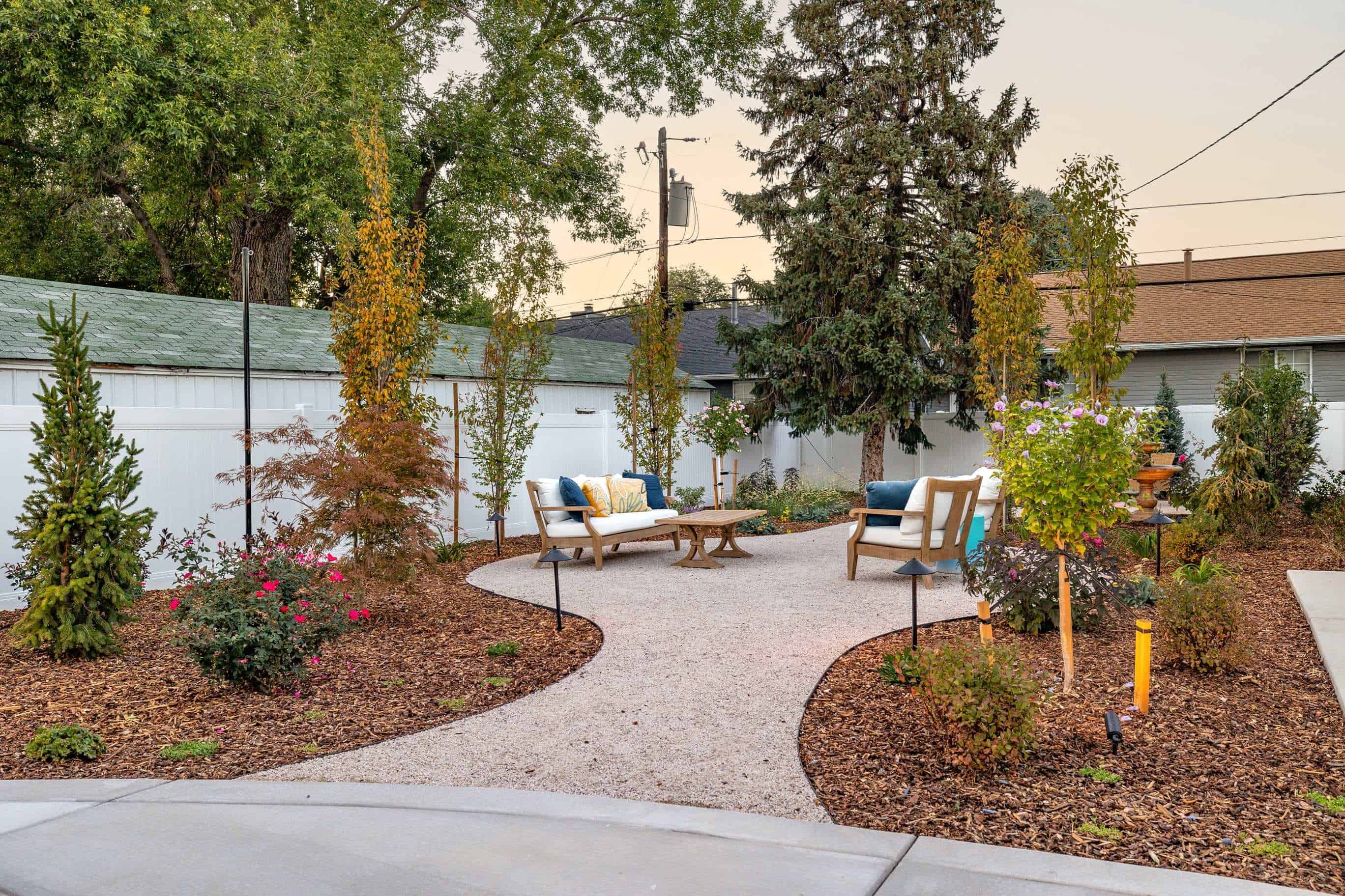 Gravel seating patio with lounge chairs, mulch beds, and layered drought-tolerant plantings