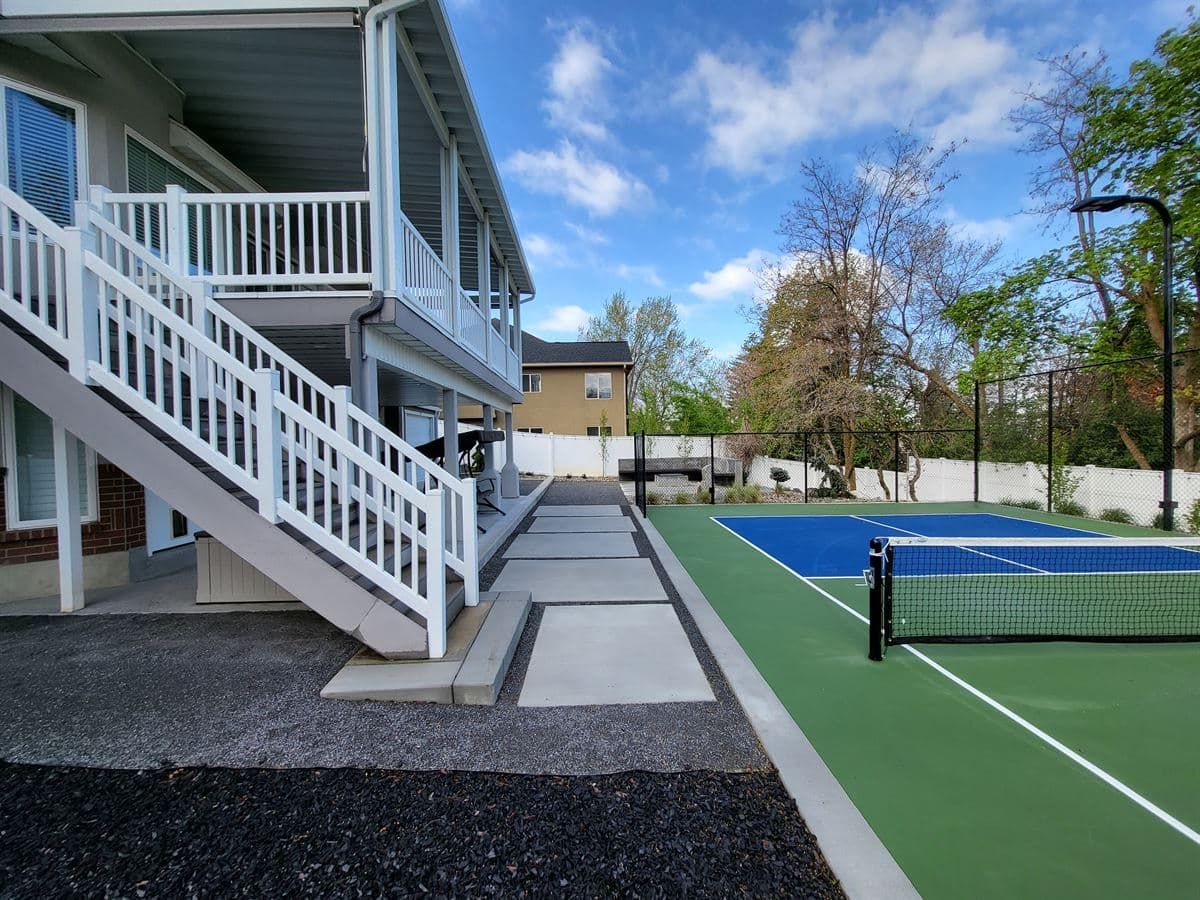 Modern concrete walkway with decorative joints leading to a backyard pickleball court in Bountiful.