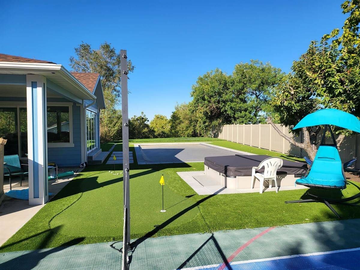 Finished backyard with artificial turf, hot tub, paver patio, and privacy fence