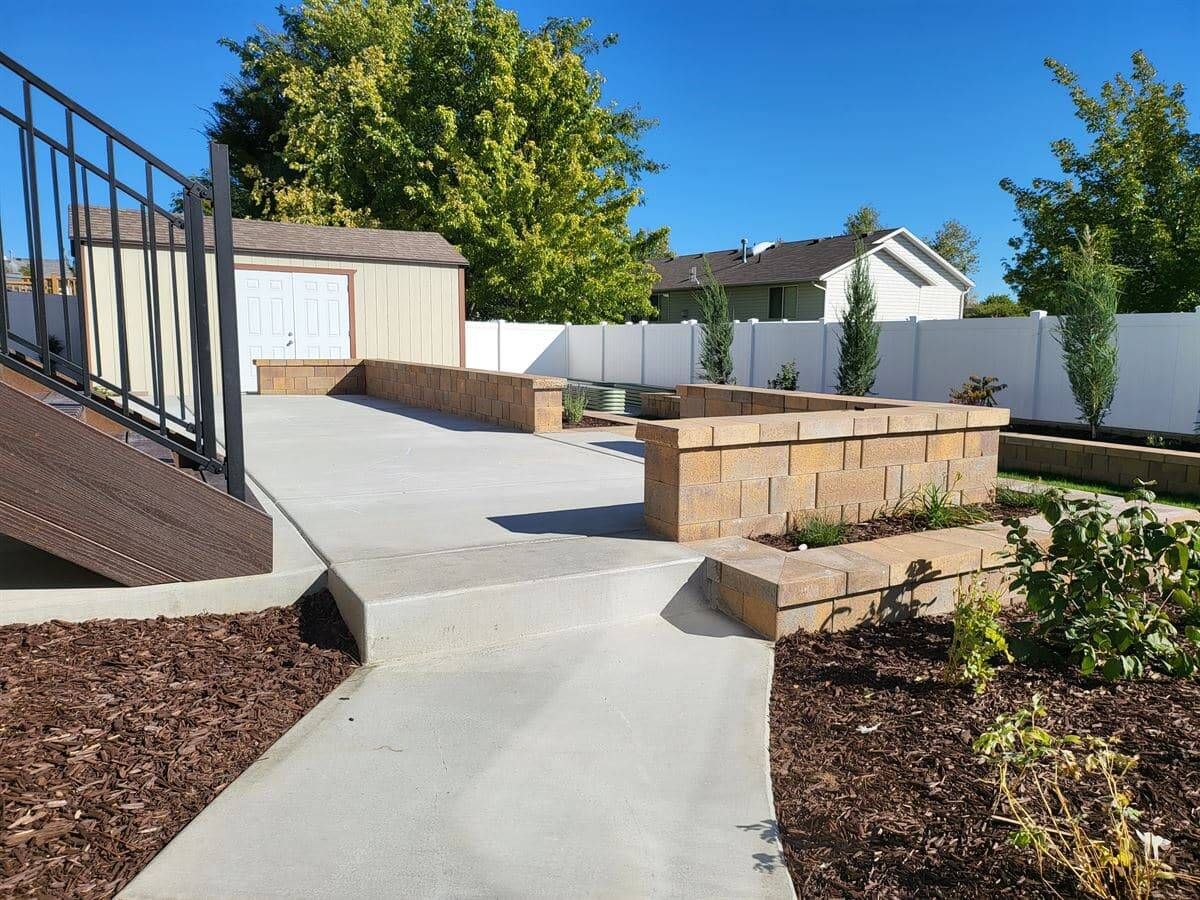 Finished concrete patio and tiered retaining walls in a landscaped backyard