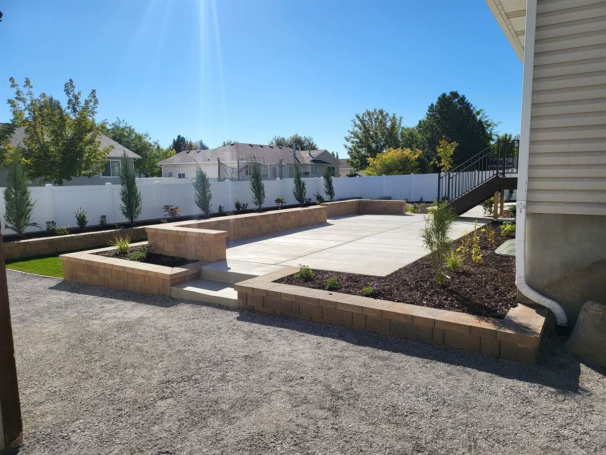 Finished concrete patio and block retaining walls in West Jordan, Utah backyard.