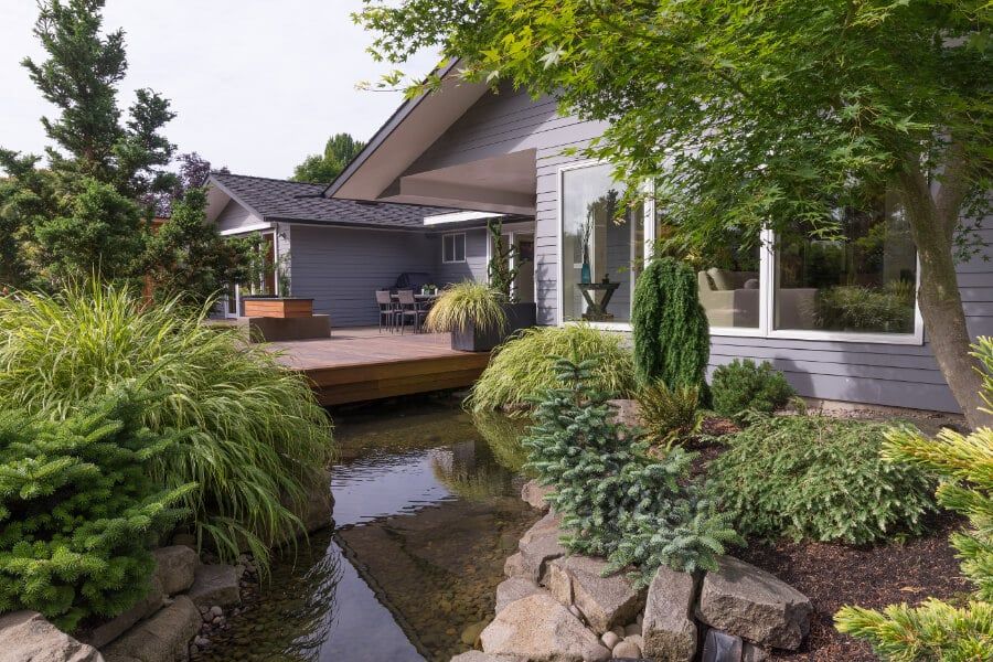 Naturalistic backyard stream water feature beside a wood deck and lush planting